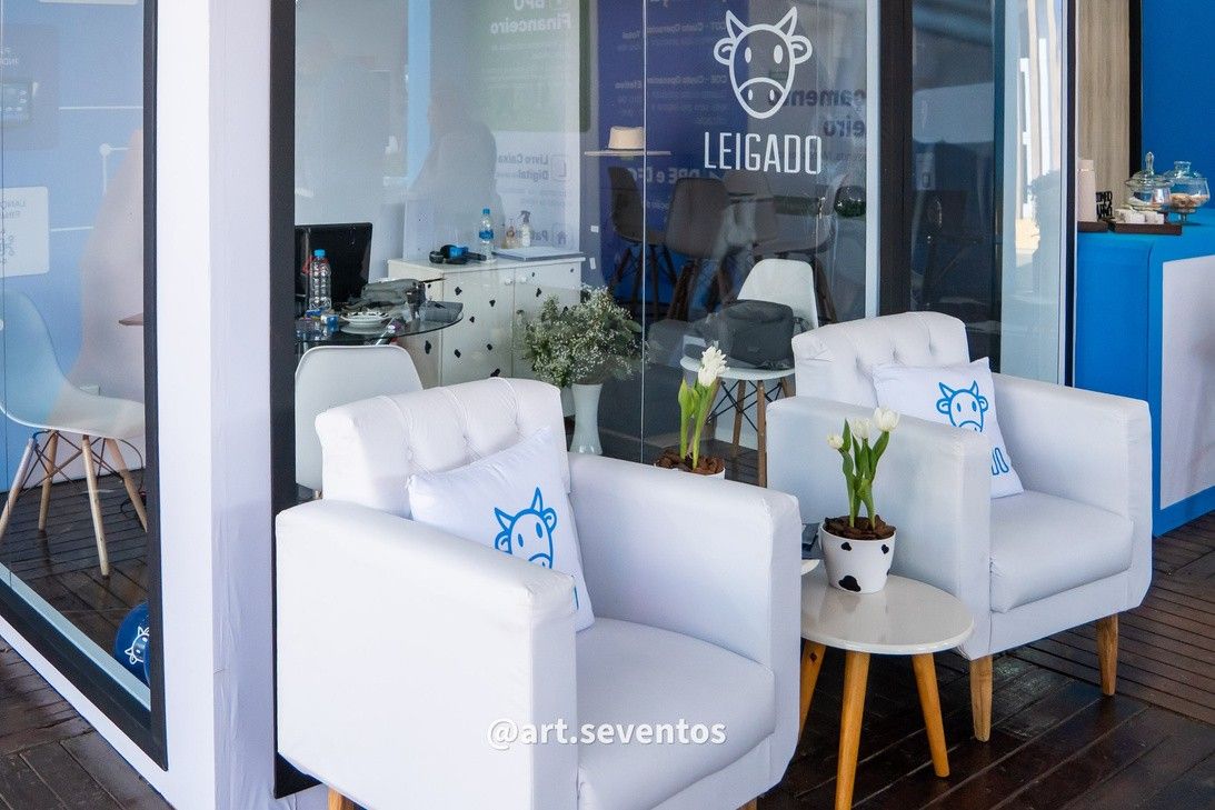 Lounge com poltronas brancas no estande Leigado